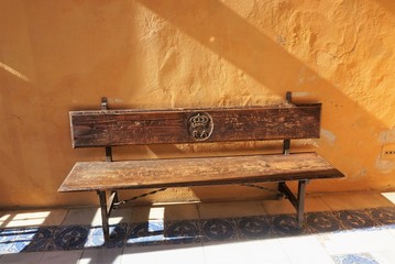 Sun-Drenched Wooden Bench in one of the Courtyards of the Real Alcázar, Seville, Spain