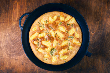 fried oatmeal pizza with cheese and spring onions in a frying pan