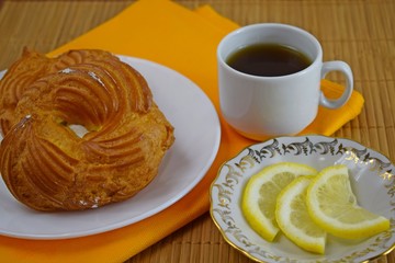 Delicious pastries.Pastry of custard dough with cream and a Cup of tea with lemon.