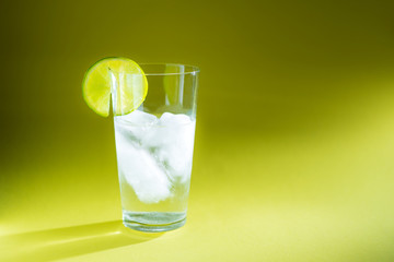 pure water in a glass of real ice and a slice of fresh lime in the rays of light