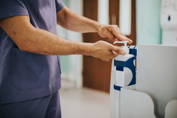 Male nurse disinfecting his hands - obrazy, fototapety, plakaty