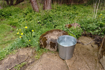 bucket of water is standing near a large stone