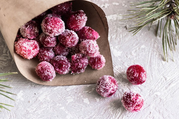 Candied cranberries in a crafting bag on the background of fir cones