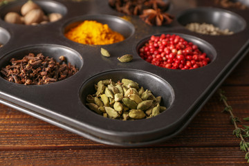 Different aromatic spices in holder on wooden table, closeup