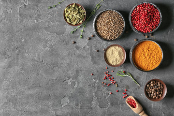 Bowls with different aromatic spices on grey background