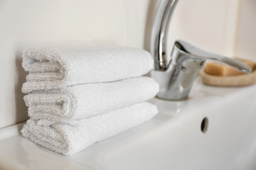 Fototapeta na wymiar Stack of clean soft towels on sink