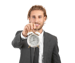 Young businessman with alarm clock on white background