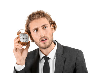 Young businessman with alarm clock on white background