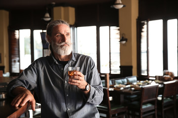 Senior man drinking whiskey in pub