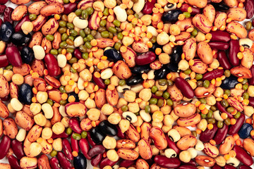 A photo of a mix of various types of legumes, shot from the top. Different beans, lentils,...