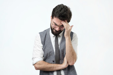 Puzzled young hispanic man looking down on gray background. The accountant is tired of compiling quarterly reports.