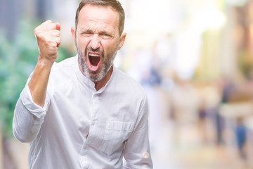 Middle age hoary senior man over isolated background angry and mad raising fist frustrated and furious while shouting with anger. Rage and aggressive concept.