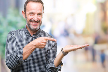 Middle age hoary senior man over isolated background amazed and smiling to the camera while presenting with hand and pointing with finger.