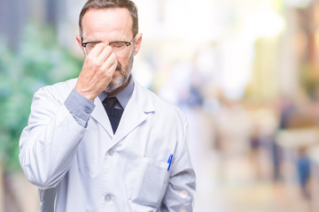 Middle age senior hoary professional man wearing white coat over isolated background tired rubbing nose and eyes feeling fatigue and headache. Stress and frustration concept.