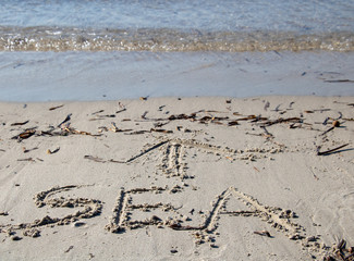 le mot mer (sea en anglais) écrit en anglais dans le sable avec une flèche indiquant la direction...