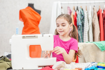 Little girl prepares a sewing machine for work, inserts a thread. Hobby sewing as a small business concept