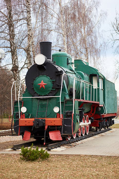 Front side view of classic old green soviet steam locomotive with red star on rail tracks