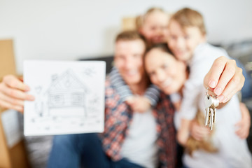 Familie hält Schlüssel als Symbol für Hauskauf
