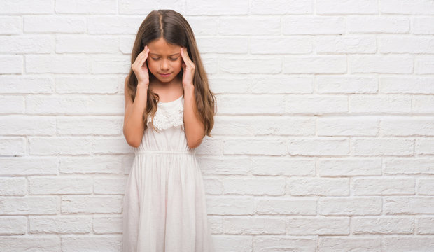 Young Hispanic Kid Over White Brick Wall With Hand On Head For Pain In Head Because Stress. Suffering Migraine.