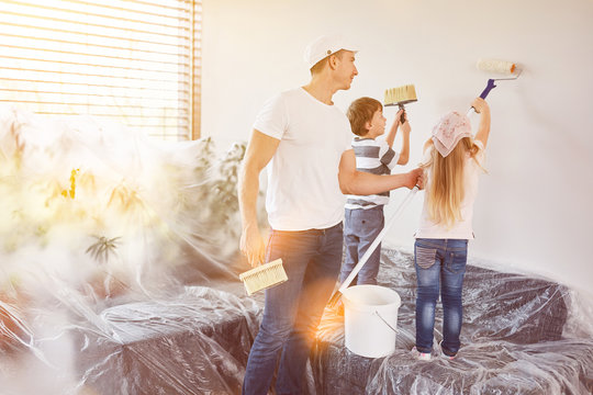 Kinder helfen Vater beim Wand streichen in Haus