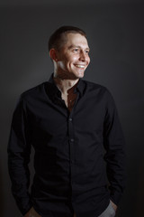 Portrait of determined goodlooking man wearing black shirt, black background.