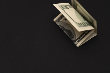 A crumpled hundred dollar bill in the corner on a black background