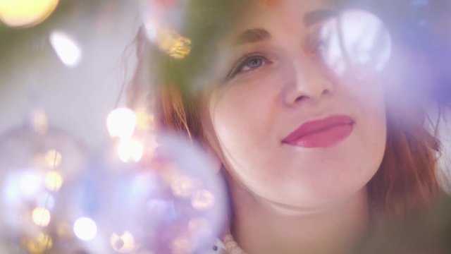 Young beautiful mysterious smiling woman looking through the lights of the garland. slow motion. 3840x2160