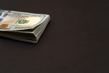 A bundle of hundred dollar bills left on a black background