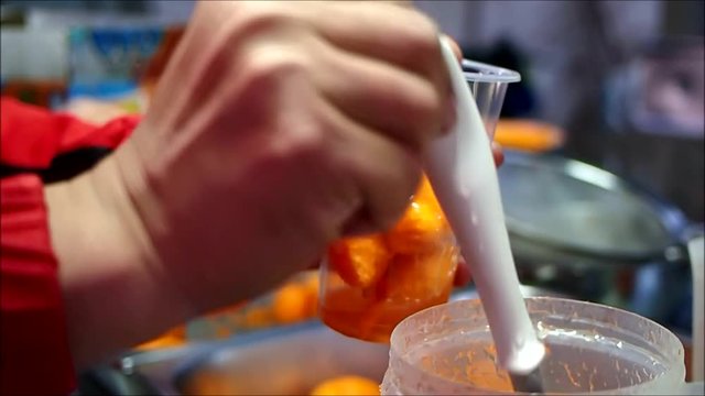 Handheld close up video shot of a man pouring sauce on deep fried quail eggs locally known as Kwek Kwek