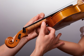 The lesson of playing the violin. Teacher helps to hold the violin