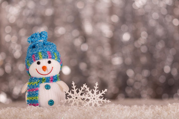 Smiling snowman and snowflakes on gray background with bokeh effect