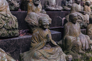 Naklejka na ściany i meble Stone statue of a seated Buddhist monk close-up