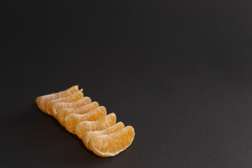 Slices of mandarin on the left on a black background