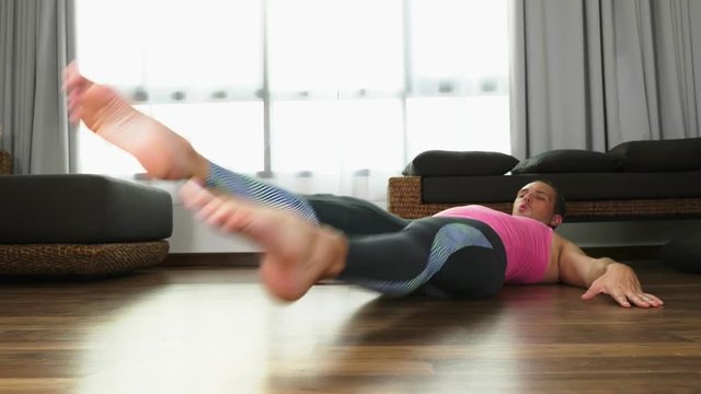Playful handsome guy in a pink t-shirt engaged in fitness, in the living room of his house.