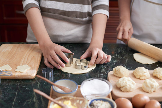 Hand of girl cutting Christmas cookies out of sweet dough