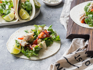 Tortillas with vegetables and white fish. Avocados, tomatoes, red onions and cod pieces sprinkled with sesame and lime juice in tortillas. Mexican food.