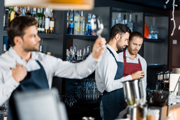 barmen team in aprons standing at workplace near counter