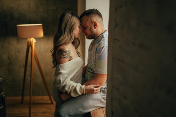 A young couple in love is hugging in front of the window face to face.