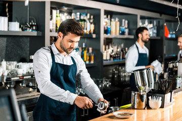handsome barista preparing coffee at wooden counter