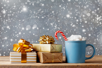 Winter lifestyle with cup of hot cocoa with marshmallows and Christmas gift or present boxes on...