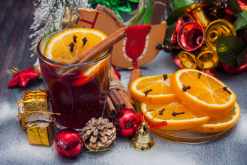 Hot wine (mulled wine) with spices on wooden background.