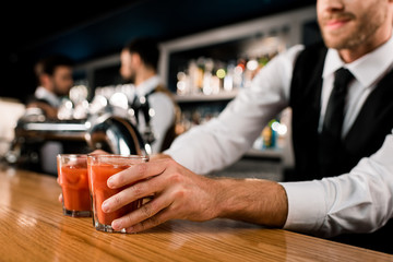 Bartender serving drinks in glasses on wooden counter