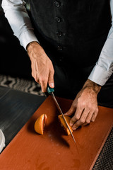 Male hands cutting fruit on cutting board with knife