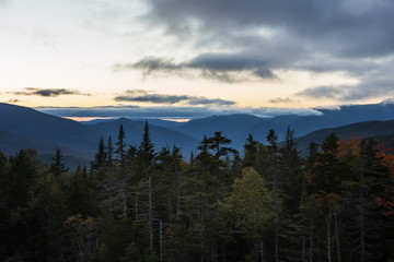 Wooded mountains and pink clouds on the peaks at sunset. White Mountain National Park. USA. New Hamshire.
