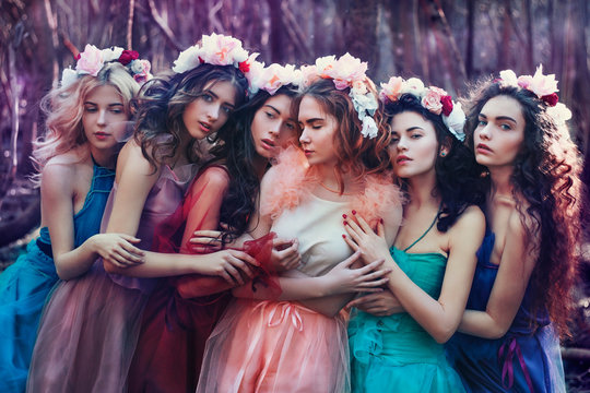 Six girls hug each other in the forest, dresses, wreaths on their heads.  Fairy forest, gentle nymphs