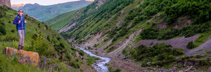Girl with a backpack in a mountain valley.