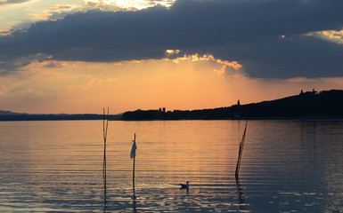 Fototapeta na wymiar Umbria, Italy, landscape of Trasimeno lake at sunset, with Isola Polvese in background on a cloudy summer day