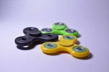 Three fidget spinners, green, yellow, black