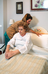 Female caregiver accommodating the pillow to elderly female patient