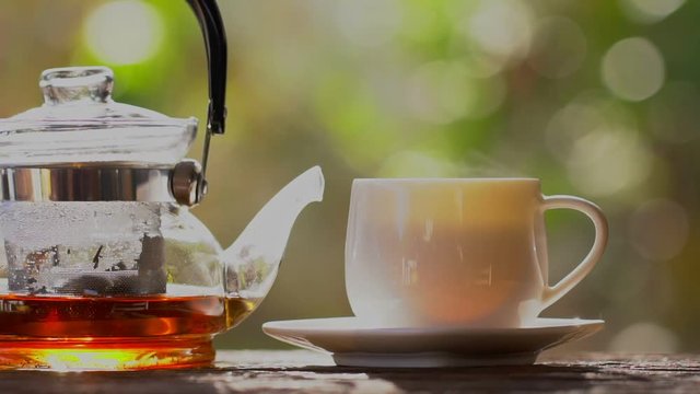 Hot green tea with tea pot with nature background,slow motion